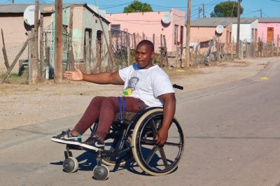 A man sitting in a wheelchair using a hand motion to direct to the right.